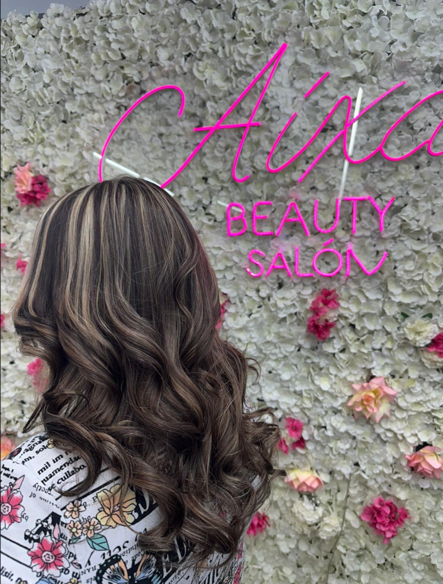 Mechas con ondas frente al muro de flores del salón